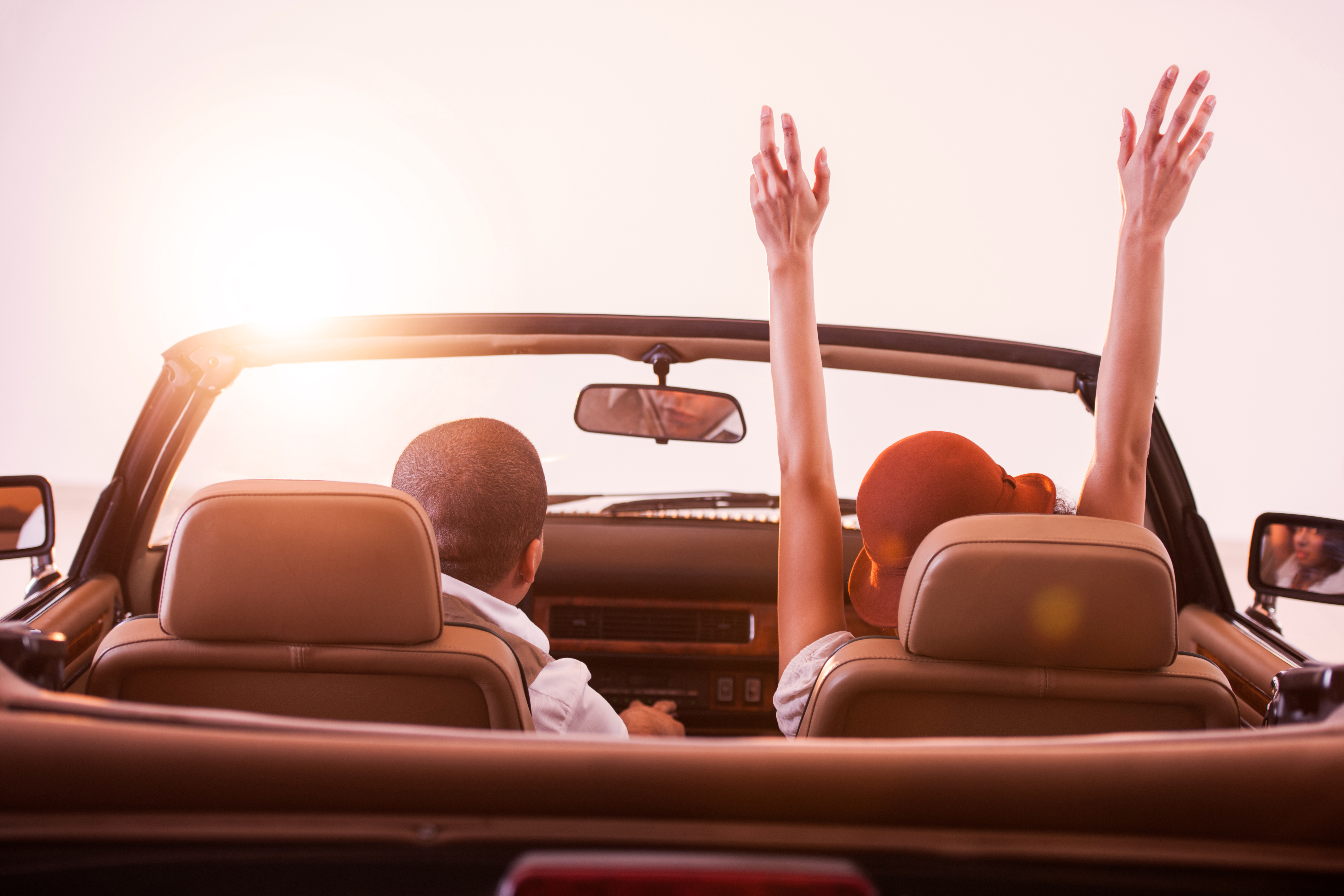 Rear view of African American couple in convertible car.