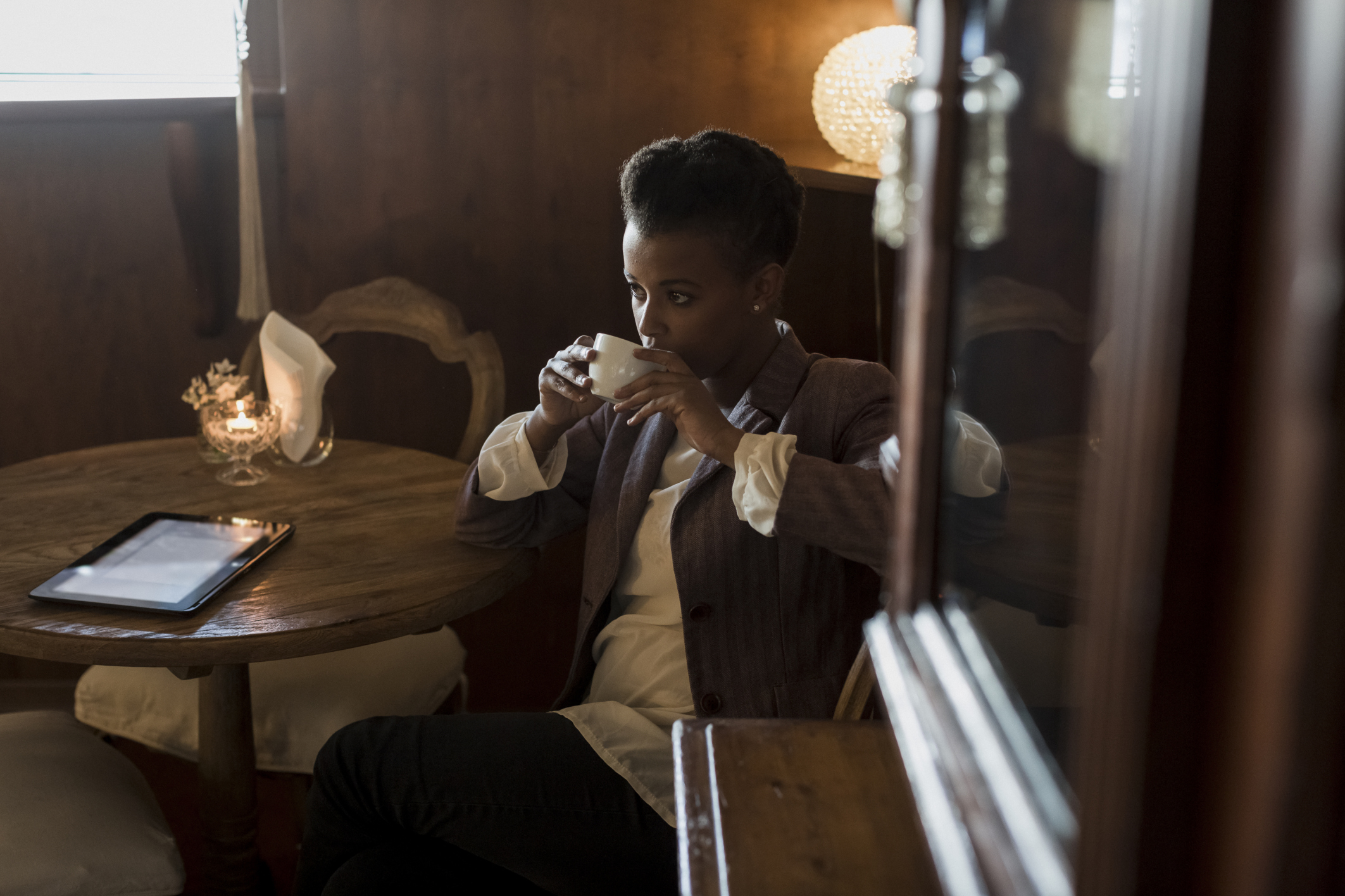 Pensive young woman sitting in a cafe drinking coffee